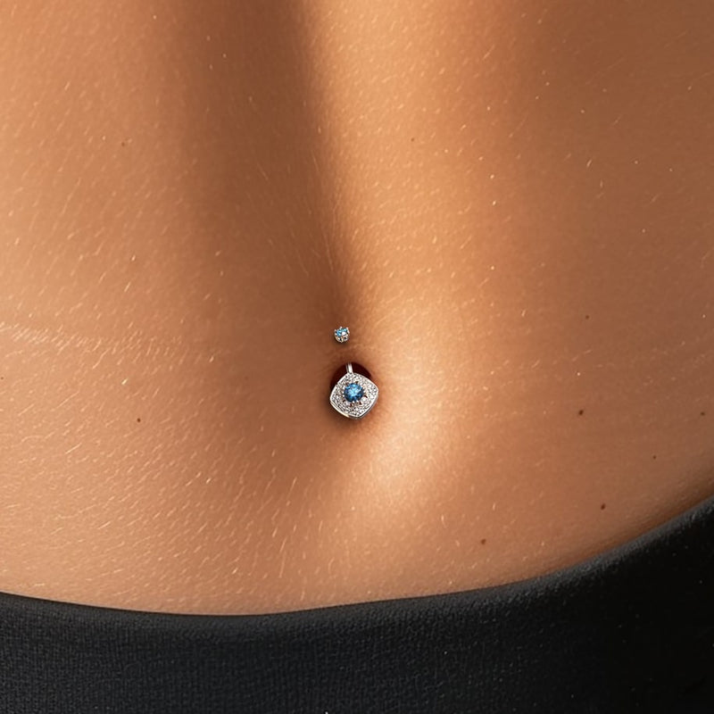 14k white gold Fleur de Chance navel ring with blue diamond shown in pierced belly for fit reference