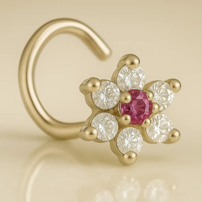 14K yellow gold CZ flower nose ring twist with red center CZ, angled side view on warm background