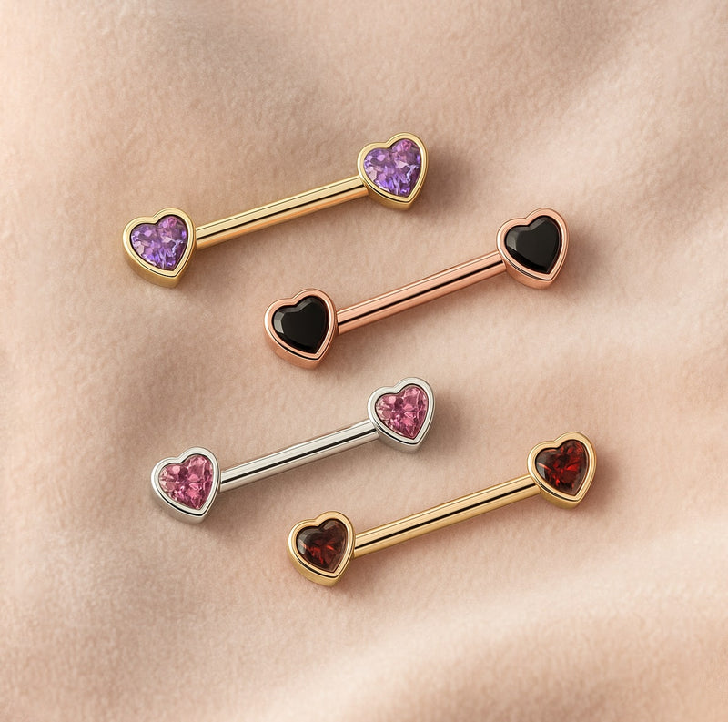 Assorted 14k gold heart nipple barbells in yellow, rose, and white gold with gemstone color options on fabric