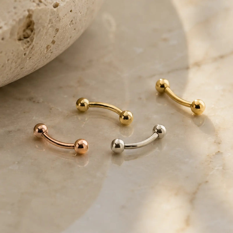 Solid 14k gold curved barbell belly and eyebrow rings lifestyle photo