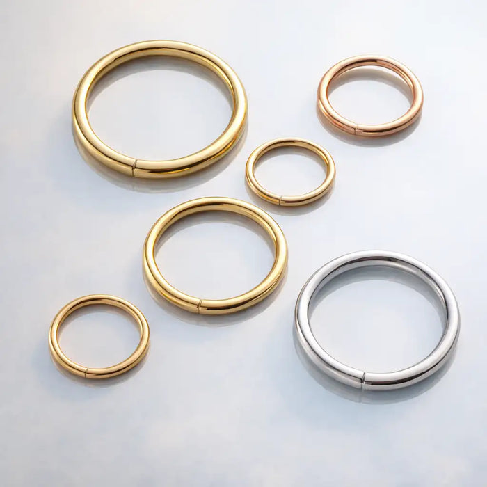 18K gold seam ring hoops in yellow, rose, and white gold shown in multiple sizes on gray surface