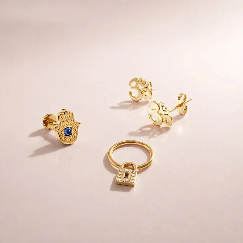 14k yellow gold diamond lock seam ring styled with hamsa and Om studs in a jewelry flat lay