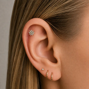 Close-up of an ear wearing multiple earrings and a diamond flower helix earring.