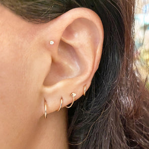 Diamond flat back stud worn in helix piercing, styled with gold hoops in a curated ear stack