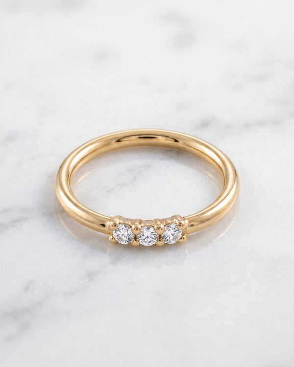 Seam rings - 14k yellow gold seamless hoop with three front-facing diamonds on white marble