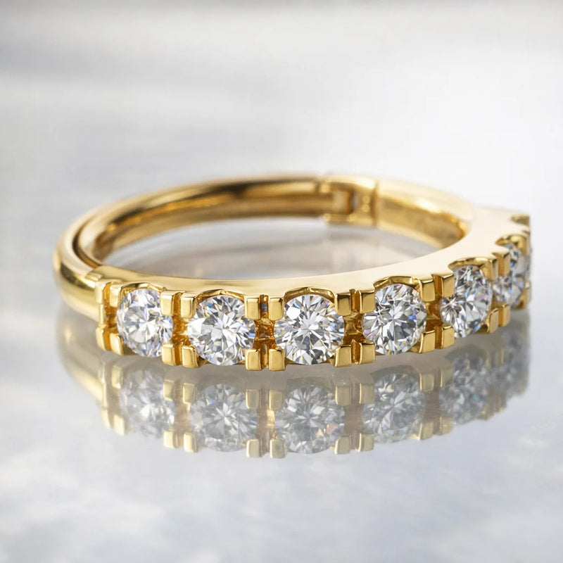 14k yellow gold CZ clicker ring resting flat on reflective marble surface, stones facing forward