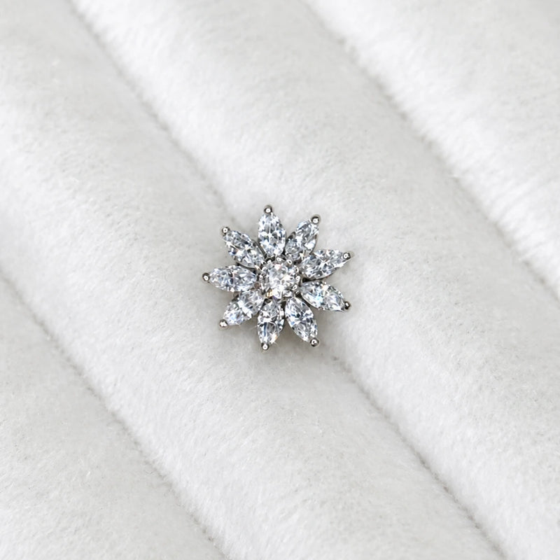 A diamond flower shaped stud, displayed on a white textured velvet ring stand.