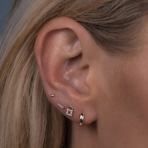 Gold milgrain bar threadless stud shown styled in a forward helix cartilage piercing on model