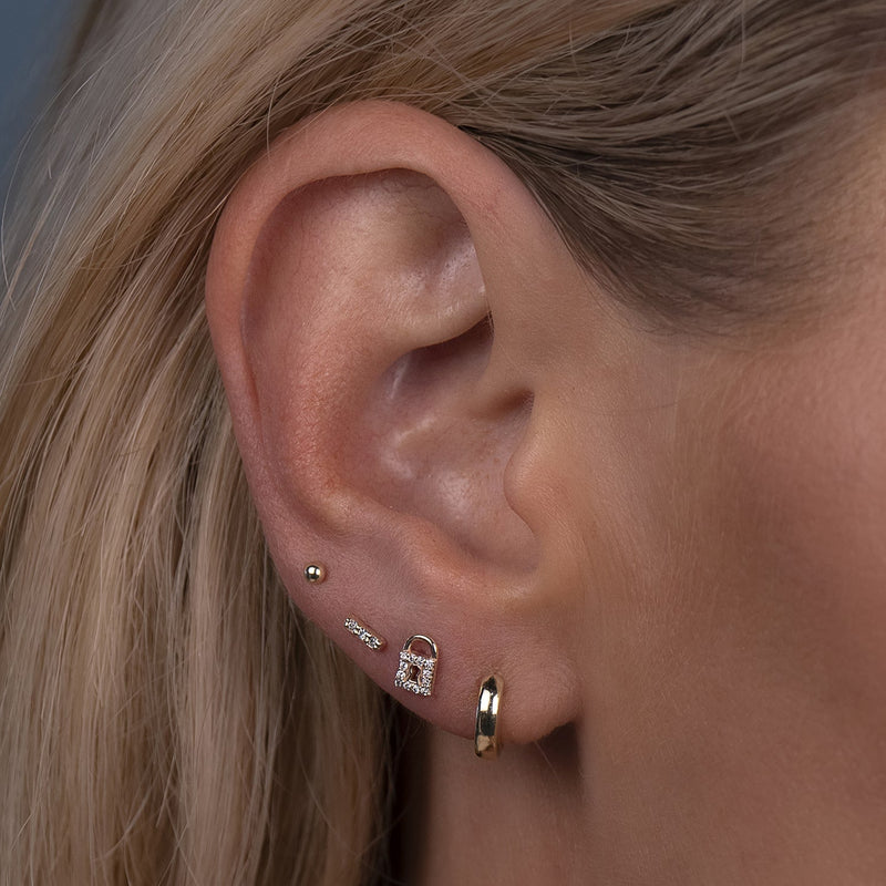 Gold milgrain bar threadless stud shown styled in a forward helix cartilage piercing on model