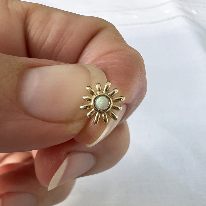14k yellow gold opal sun push pin end held for size reference, showing ray detail
