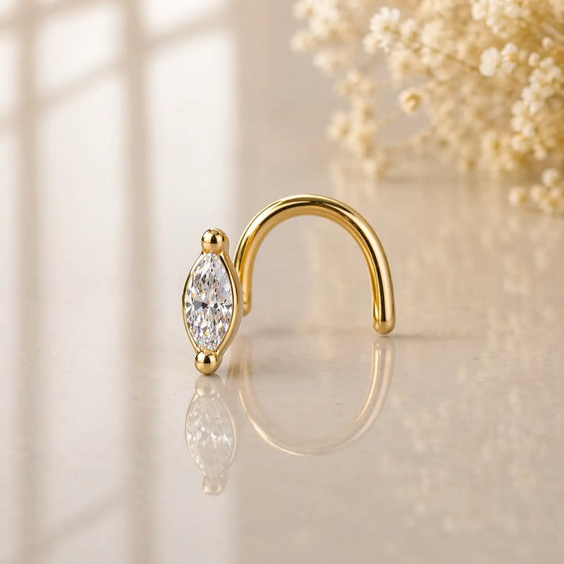14k yellow gold marquise diamond twist nose ring with two-prong setting on reflective surface