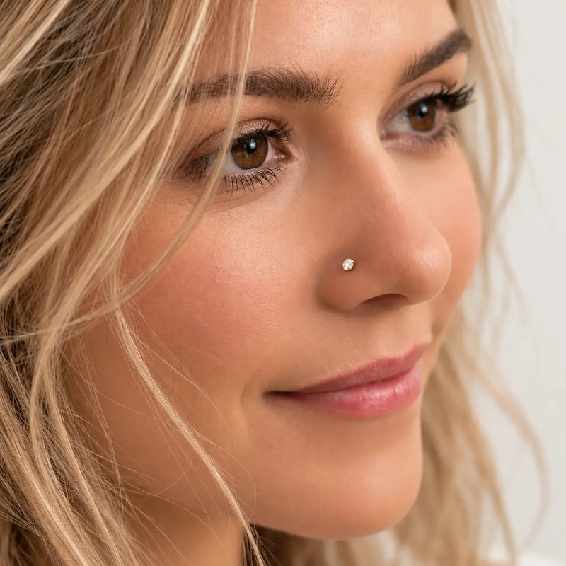 Model wearing a 3mm diamond prong-set nose stud in solid gold, side profile close-up
