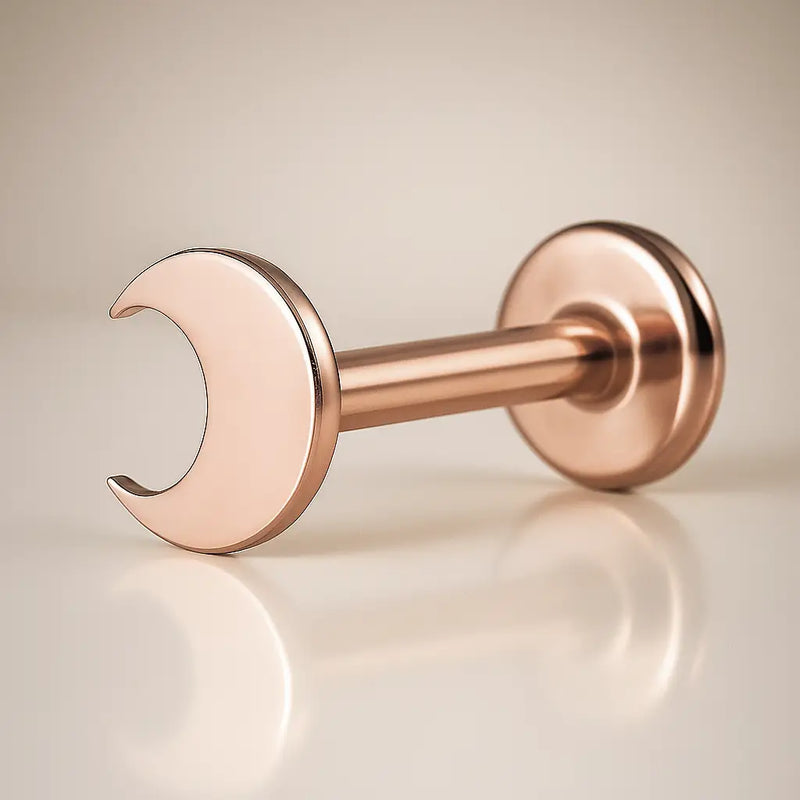 14K rose gold crescent moon flat back labret, angled view showing warm blush tone and disc backing