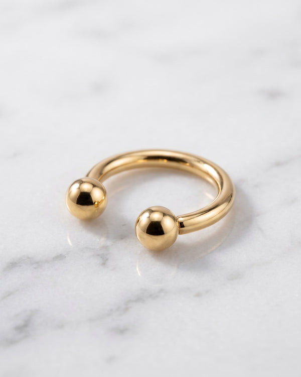 Circular barbells - 14k yellow gold horseshoe circular barbell on white marble