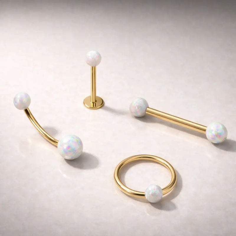 14k yellow gold white opal body jewelry collection showing labret, barbell, curved barbell, and captive ring