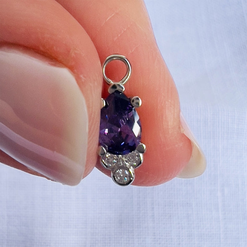 Pear amethyst and diamond piercing charm held between fingers to show dainty size reference