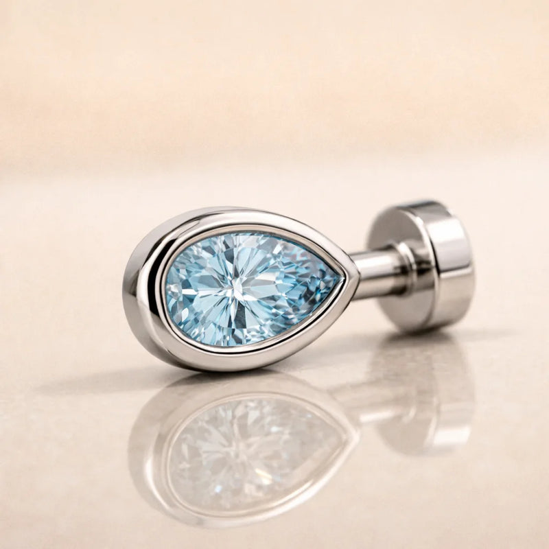 14k white gold aquamarine pear-cut floating belly ring laying on side, top view