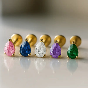 Five pear-cut flat back studs in yellow gold lined up showing pink, blue, clear, purple, and green stone options
