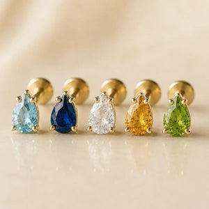 Five pear-cut flat back studs in yellow gold lined up showing pink, blue, clear, purple, and green stone options