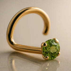 14K yellow gold peridot nose ring twist style with prong-set green stone, angled studio view