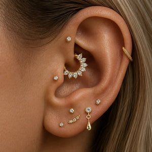 14K yellow gold dew drop labret stud worn in lobe piercing, styled with curated gold ear stack