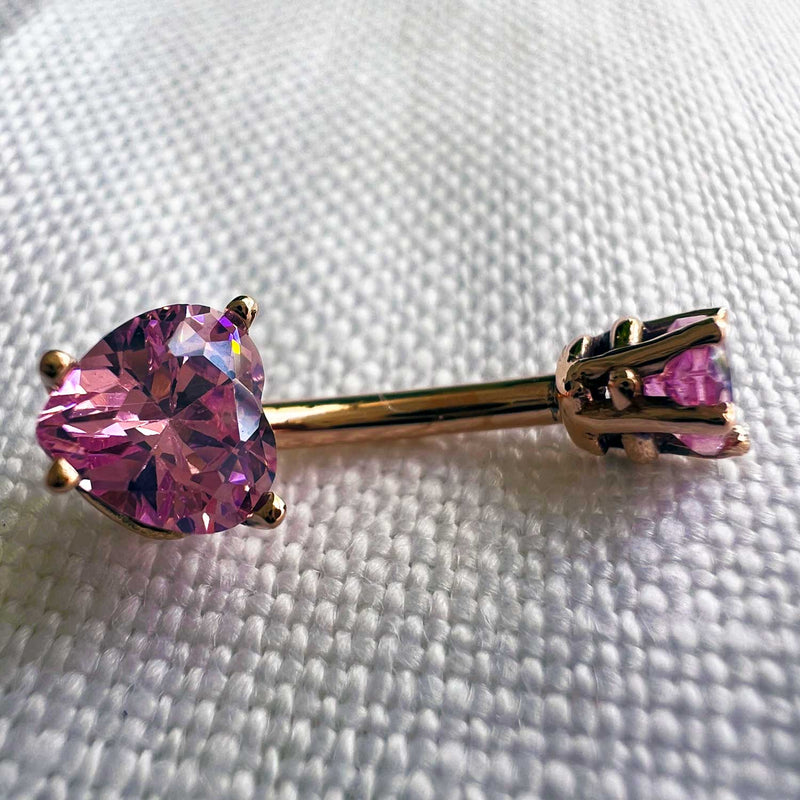 14k rose gold navel ring with pink heart CZ stones shown lying flat for size reference