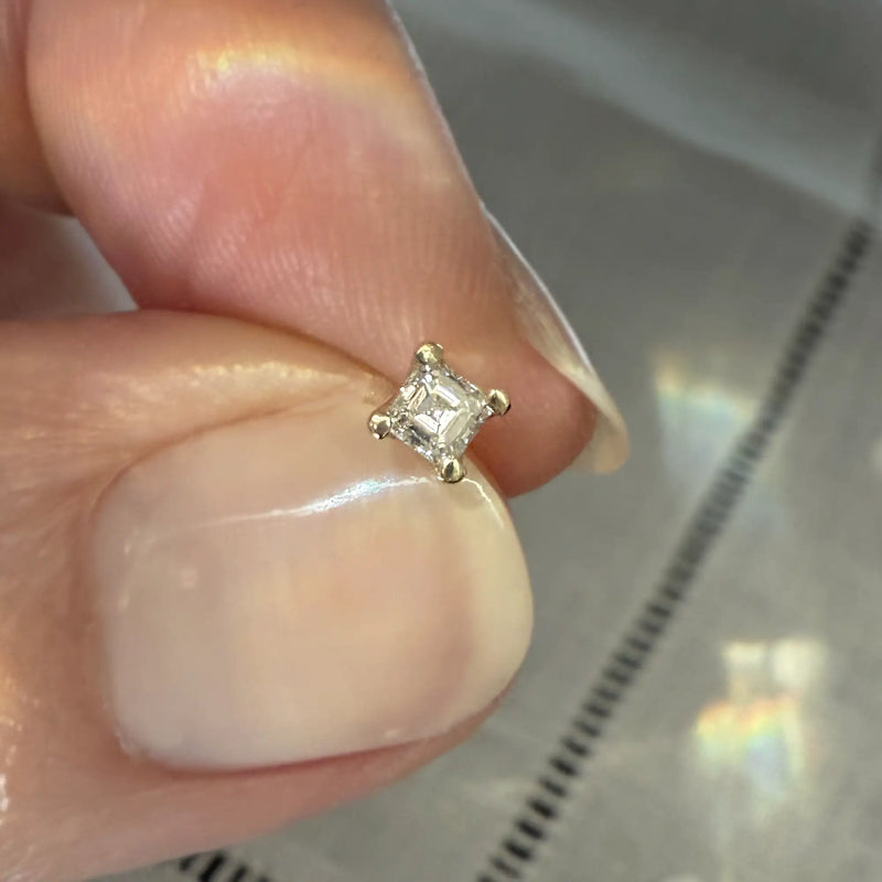 14k yellow gold 2.5mm princess-cut diamond stud end held between fingers to show actual size