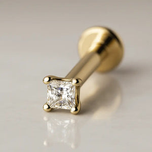 14k yellow gold 1.5mm princess-cut diamond flat back labret stud, angled hero shot on marble surface