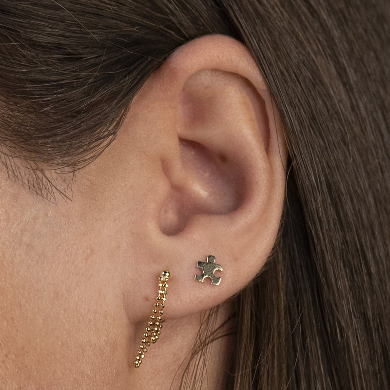 14k gold puzzle piece threadless stud shown in a helix ear piercing on a model for fit reference