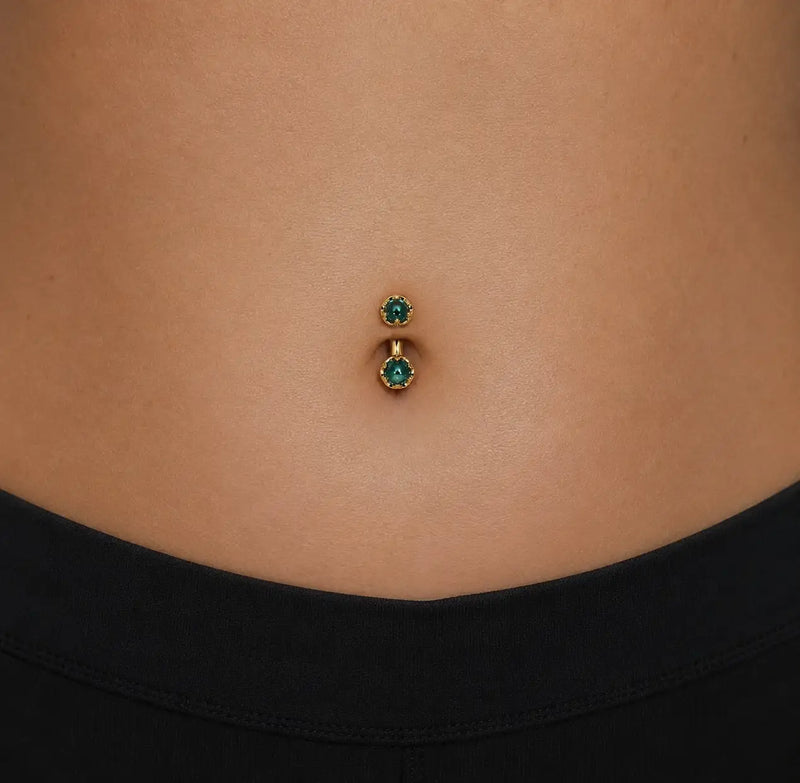 Model wearing the Reina London Blue Topaz Crown Curved Belly Ring in 14k gold