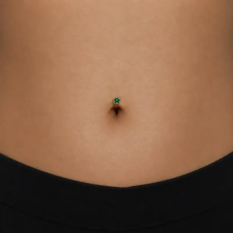 Model wearing the Reina Zambian Emerald Crown Floating Navel Ring in 14k gold