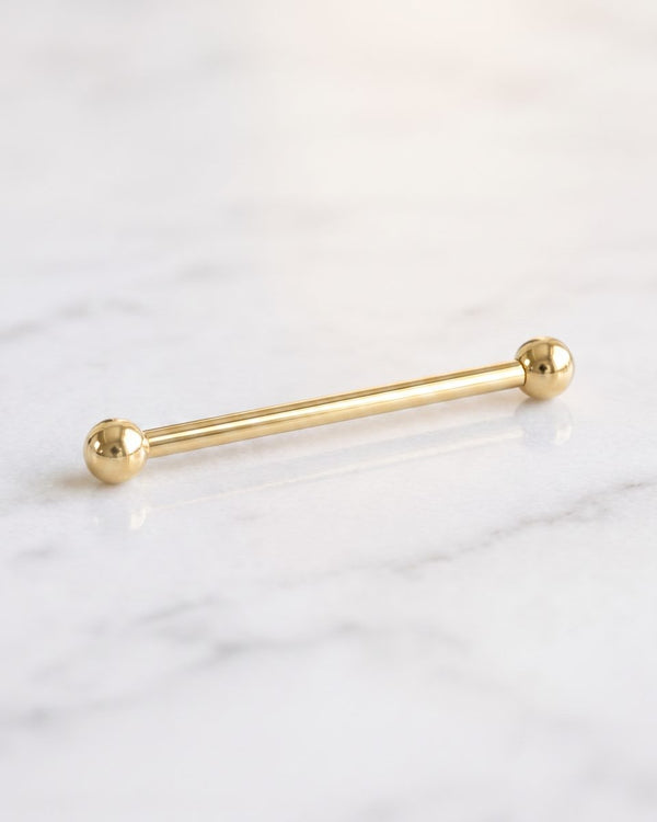 Industrial barbells - long plain 14k yellow gold Classic Industrial barbell with ball ends on white marble
