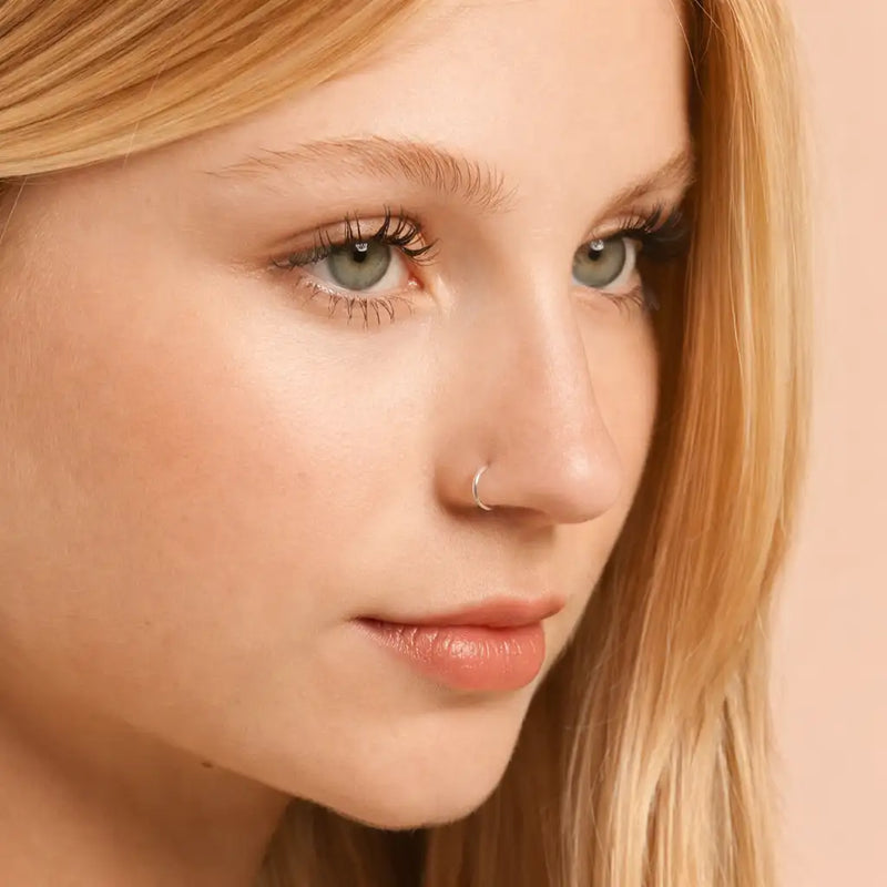 Dainty platinum seam ring hoop worn in nose piercing on model, showing minimal elegant fit