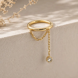 Diamond and yellow gold, a shanty seam ring lifestyle image dangling on a stone surface.