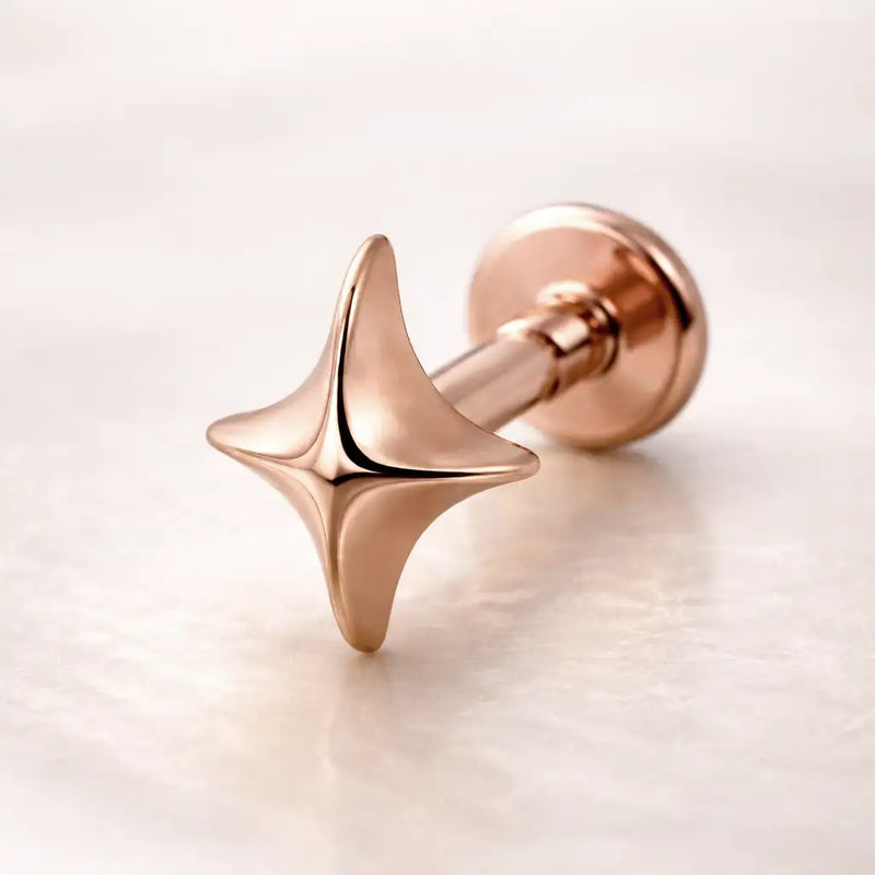 14k rose gold sparkle flat back stud with polished four-point star charm, angled view on marble surface