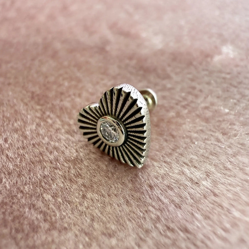 Close-up of 14k white gold diamond sunburst heart flat back stud resting on pink textured surface