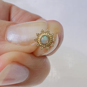 14k yellow gold opal sunburst piercing stud held between fingers for size reference