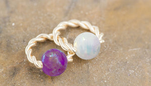 Purple and white opal twisted 14K gold captive bead rings side by side showing opal color options