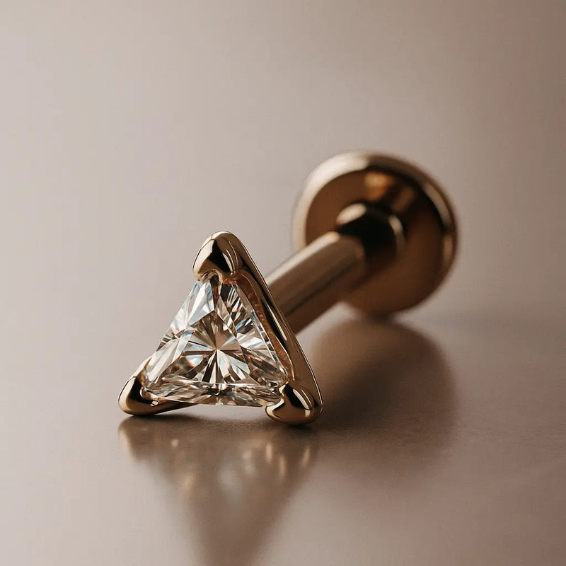 14k rose gold 3mm triangle diamond flat back labret stud, angled lifestyle shot on warm background