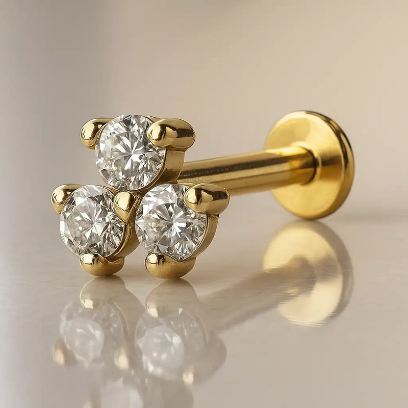 14k yellow gold triple CZ flat back labret with three prong-set stones, angled side view on reflective surface