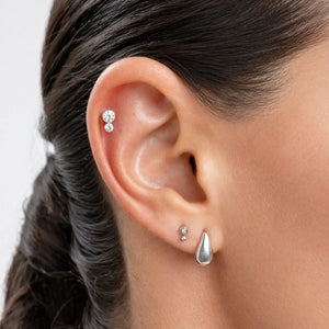 Diamond bubble flat back labret stud worn in cartilage piercing, styled with additional ear jewelry on model