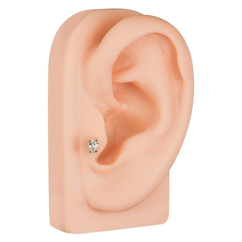 Pear diamond 14k gold cartilage stud shown in lobe piercing on silicone ear model for size reference