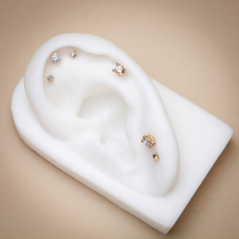 14k gold princess cut diamond cartilage stud shown on white ear model with curated piercing stack