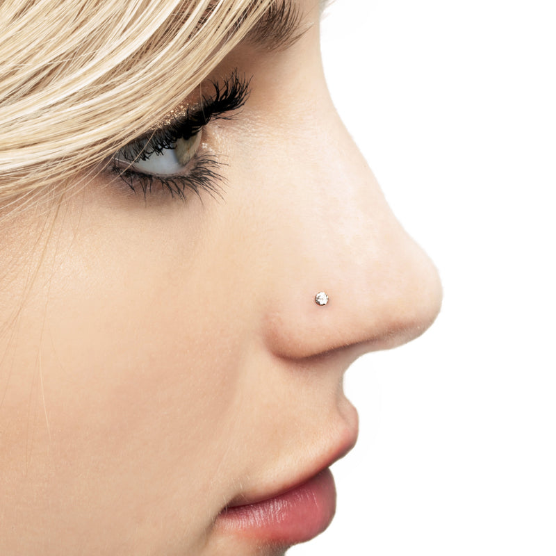 Close-up side profile of 2mm CZ 14k gold nose stud worn in nostril piercing, minimal and delicate