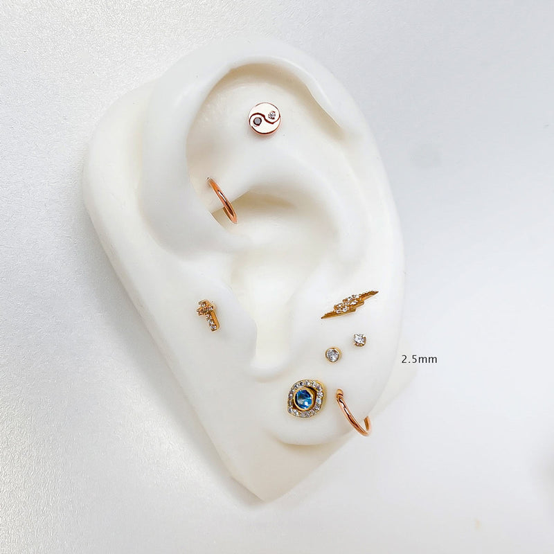 2.5mm diamond bezel flat back stud labeled on white ear mannequin in a styled multi-piercing display