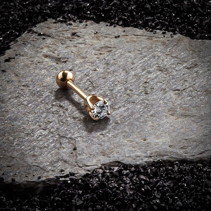 14k yellow gold 2mm CZ cartilage stud on dark rock surface, showing high-set prong basket profile
