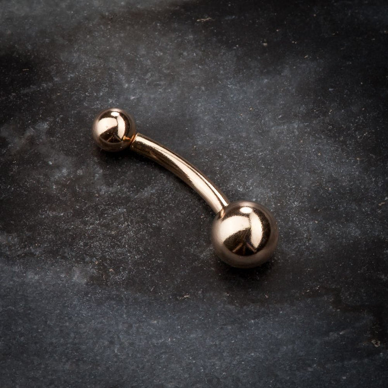 14k rose gold classic double ball belly ring on dark stone surface, angled product view