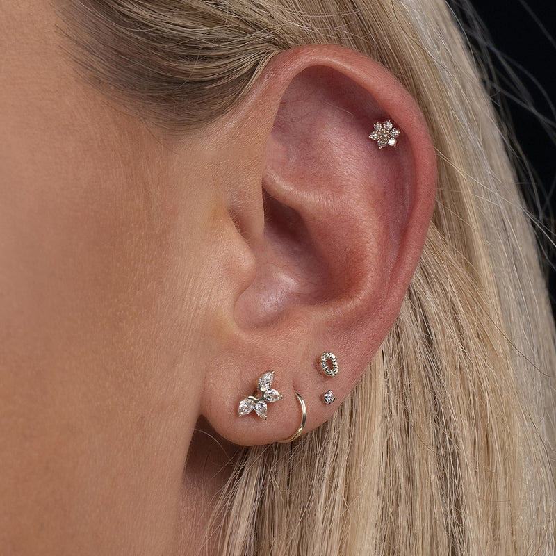 CZ halo flat back earring worn in second lobe piercing as part of a layered ear curation on model