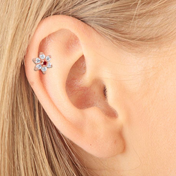 14k rose gold CZ flower stud with red center stone worn in helix piercing, close-up on model