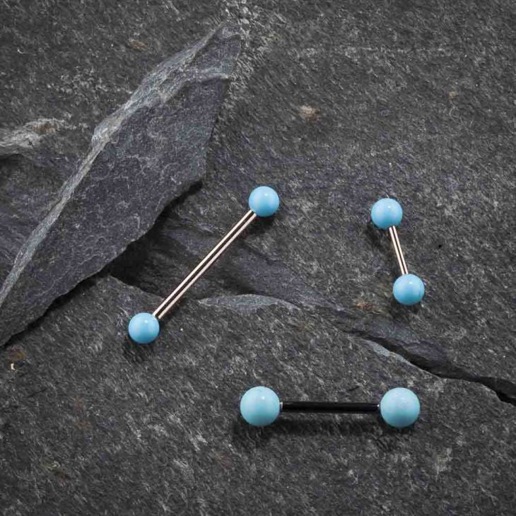 Multiple simulated turquoise straight barbells in varied metal tones displayed on dark slate stone surface